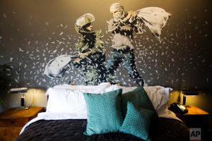 A Banksy wall painting showing Israeli border policeman and Palestinian in a pillow fight is seen in one of the rooms of the "The Walled Off Hotel" in the West Bank city of Bethlehem, Friday, March 3, 2017. The owner of a guest house packed with the elusive artist Banksy's work has opened the doors of his West Bank establishments to media, showcasing its unique "worst view in the world." The nine-room hotel named "The Walled Off Hotel" will officially open on March 11. (AP Photo/Dusan Vranic)